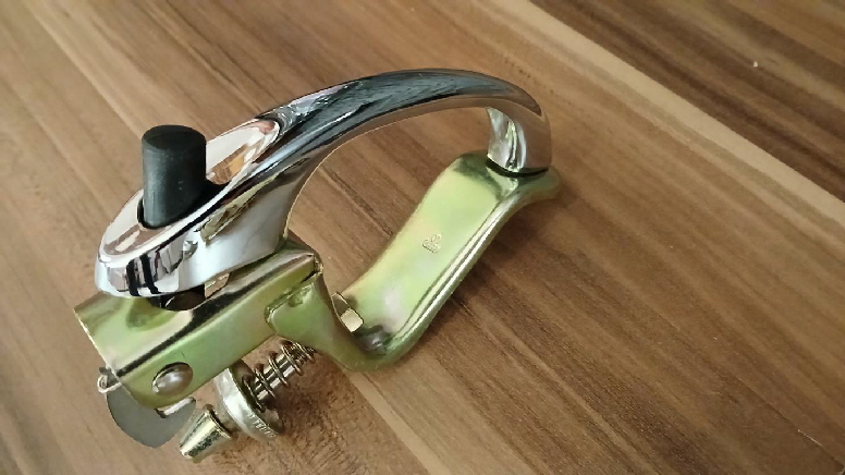 Die Fronthaubengriffmechanik in galvanisch gelb verzinkt. Der Chromgriff wird daran festgeschraubt. Mein Käfer-Modell hat am Frontgriff und am Öffner für die Motorklappe hinten, jeweils einen schwarzen Druckknopf. Für hinten ohne Schloss.